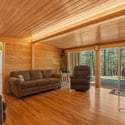 Cozy, wood-paneled living space with two sliders offering abundant natural light and scenic forest views.