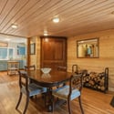 Cozy dining area with warm wood accents, featuring a wood stove and seamless flow to the kitchen.
