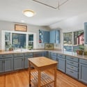 Bright and spacious kitchen featuring custom cabinetry, ample countertop space, and large windows overlooking the yard.