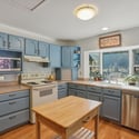 Bright kitchen featuring blue cabinetry, modern appliances, and abundant natural light for a welcoming cooking space.