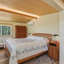 Bright and airy bedroom featuring large windows, natural wood accents, and cozy seating for relaxation.