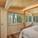 Bright and airy bedroom featuring expansive windows that invite natural light and views of surrounding nature.