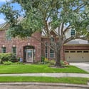 Stunning brick home featuring lush landscaping, spacious driveway, and ample outdoor space for entertainment.