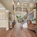 Spacious entryway featuring inviting high ceilings, rich wood flooring, and a striking staircase centerpiece.
