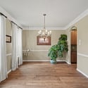Spacious dining area with ample natural light, featuring a chandelier and lush greenery for a vibrant atmosphere.