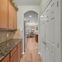 Modern kitchen with rich wood cabinetry, leading into a spacious living area filled with natural light.