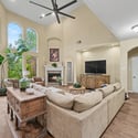 Bright and inviting living room with high ceilings, fireplace, and large windows showcasing beautiful outdoor views.