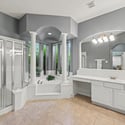 Spacious bathroom featuring a large soaking tub, dual vanities, and natural light from expansive windows.