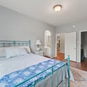 Bright and welcoming bedroom featuring a cozy layout, vintage metal bed frame, and ample natural light.
