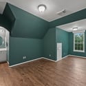 Bright, spacious room featuring unique architecture, hardwood floors, and an adjoining bathroom setup for convenience.