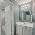 Modern bathroom featuring a spacious vanity, circular mirror, and calming blue walls for a refreshing ambiance.