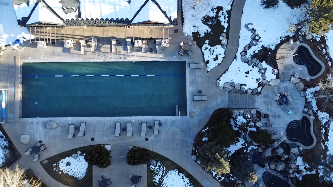 39 of 42. Expansive outdoor pool area featuring spacious lounging options, surrounded by picturesque landscaping and winter ambiance.