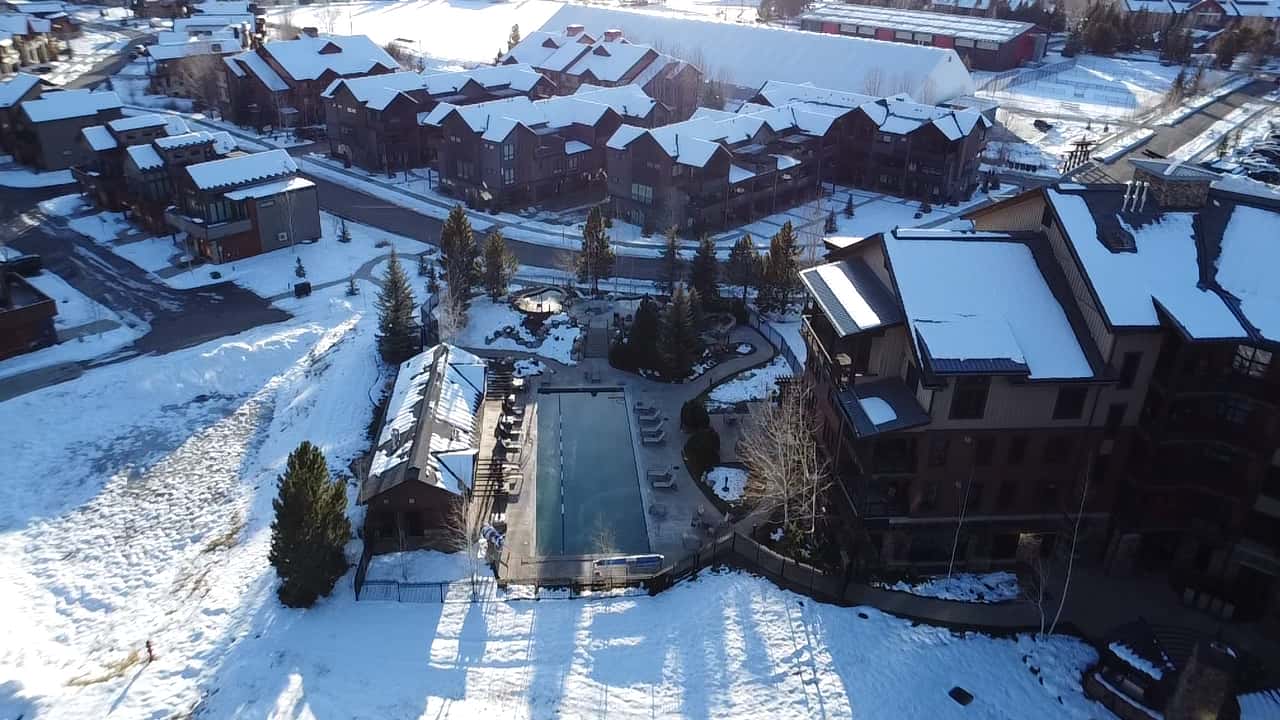 40 of 42. This modern property features a spacious outdoor pool surrounded by snow-covered landscape and nearby amenities.