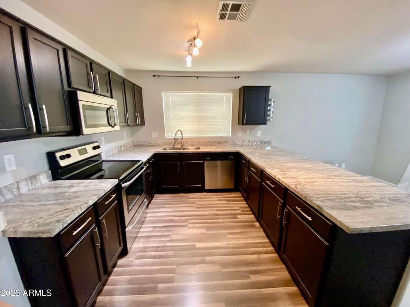 4 of 16. Stylish kitchen with granite countertops, stainless steel appliances, dark cabinets, and generous workspace. An ideal setup for cooking, hosting, and family gatherings.