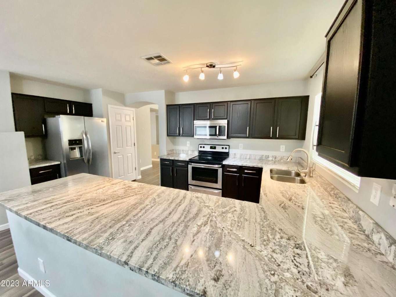 6 of 16. Well-appointed kitchen featuring extensive granite surfaces, stainless steel appliances, abundant storage, and a practical layout designed for modern living.