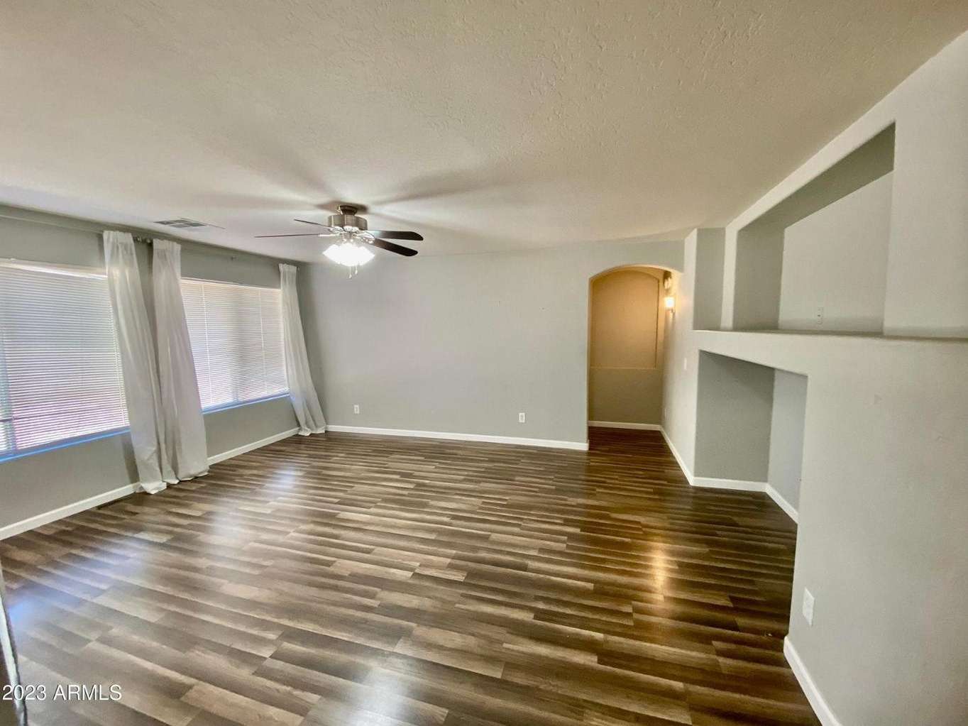 12 of 16. Expansive great room featuring durable wood-look flooring, large windows, and decorative built-in niches. The open layout creates a welcoming environment for relaxing and entertaining.