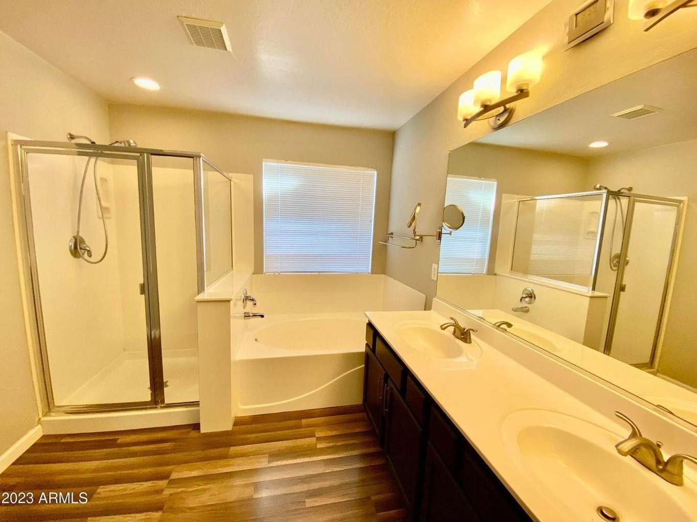 13 of 16. Elegant primary bathroom showcasing dual sinks, separate shower, soaking tub, and spacious vanity. A private retreat designed to complement the home's comfortable lifestyle.