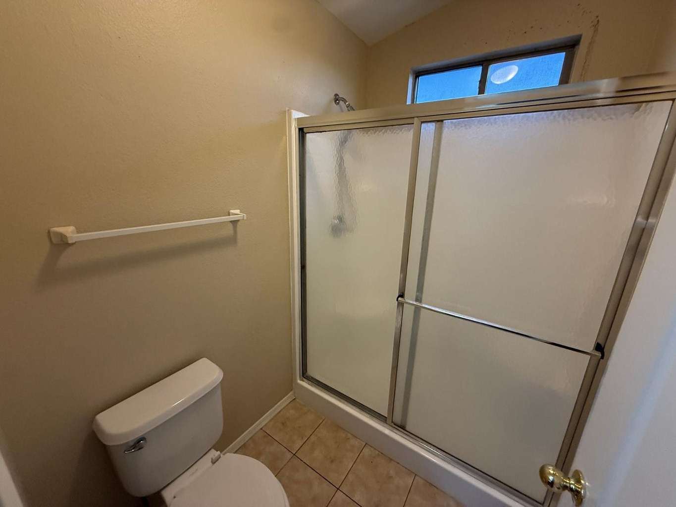 2 of 22. Well-maintained bathroom with a full-size shower, sliding glass enclosure, and tile flooring. Natural light enhances the space while neutral tones provide timeless appeal.