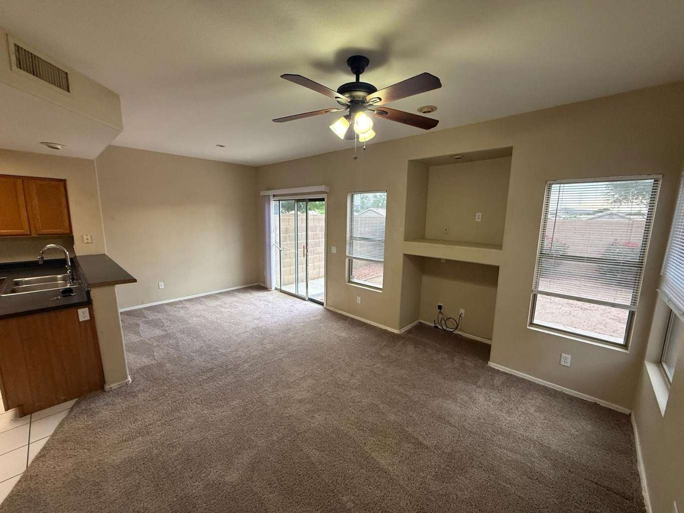 5 of 22. Open living and dining area featuring large windows, backyard views, and direct patio access. Built-in media space adds convenience and flexibility for modern living.