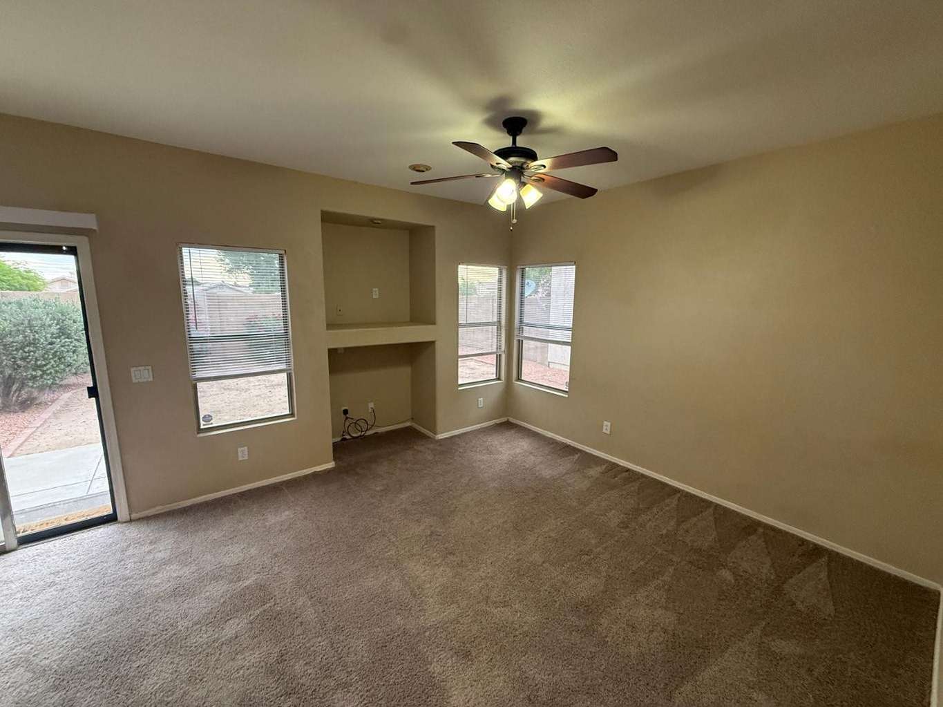 6 of 22. Comfortable family room with a built-in niche, plush carpeting, and multiple windows that bring in natural light. An excellent setting for movie nights, gatherings, or quiet evenings at home.