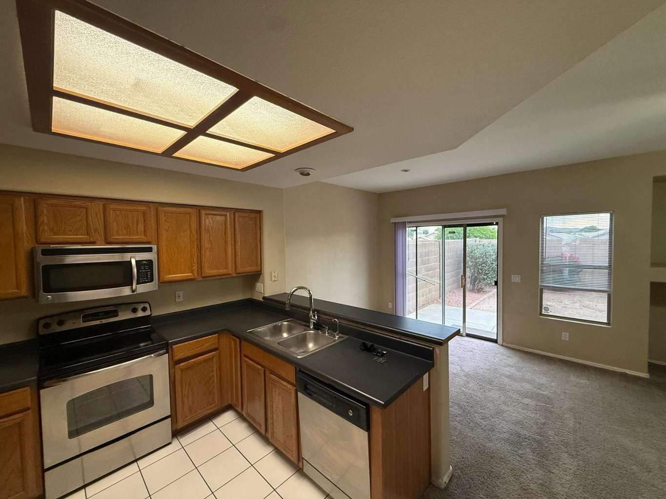 11 of 22. Bright kitchen featuring stainless steel appliances, extensive cabinet storage, and a breakfast bar that seamlessly connects to the living room. Backyard access enhances indoor-outdoor living opportunities.