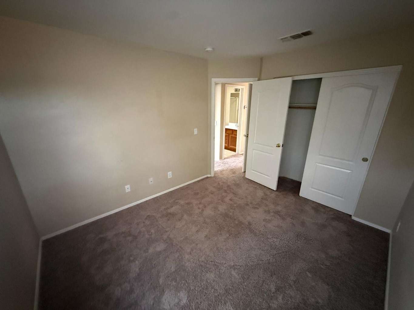 19 of 22. Comfortable bedroom with neutral d cor, plush carpeting, and convenient closet storage. A versatile space suitable for family, guests, or a home office setup.