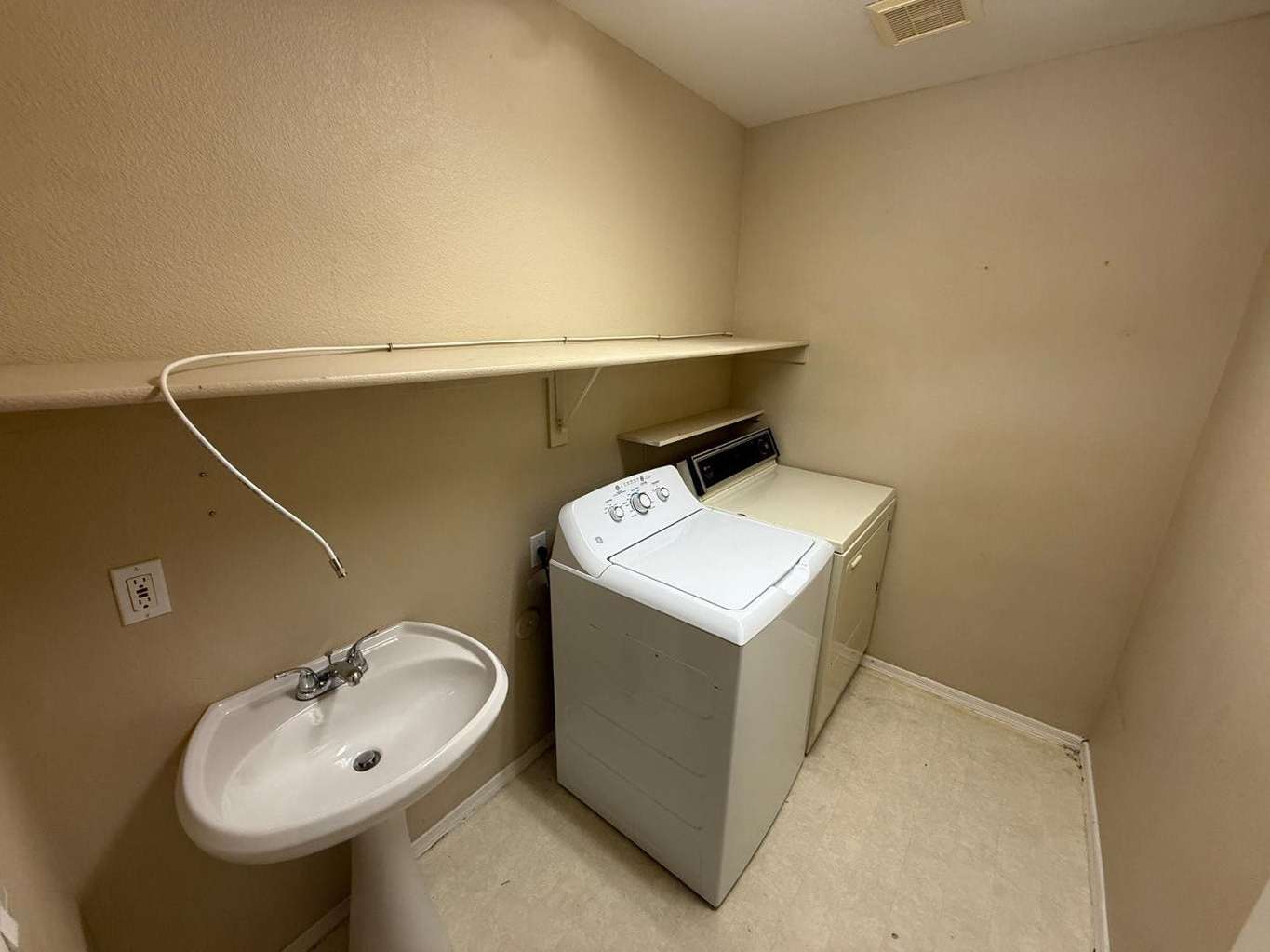 20 of 22. Dedicated laundry area featuring washer and dryer hookups, utility sink, and storage shelving. A practical space that adds convenience and efficiency to daily household tasks.