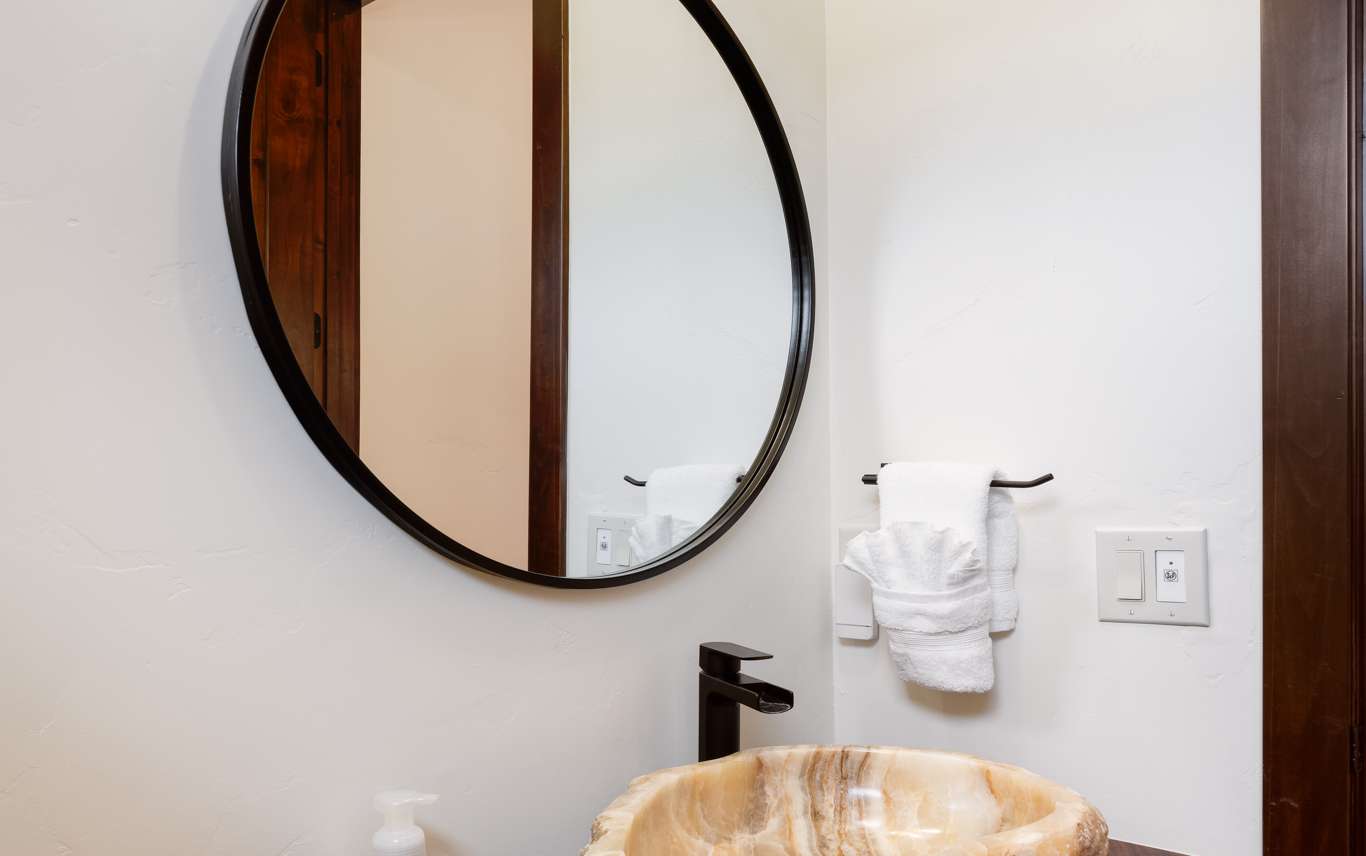 14 of 42. This unique bathroom features a natural stone sink and a modern circular mirror, enhancing its distinctive design.