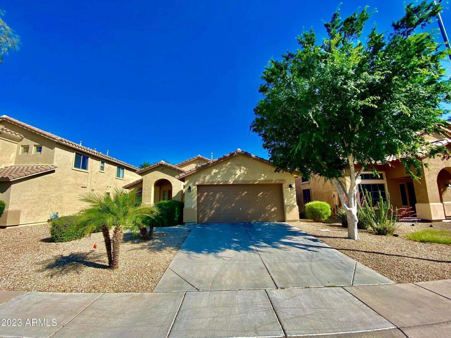 1 of 16. Beautiful exterior view highlighting the home's attractive architecture, covered entry, mature landscaping, and attached garage. A move-in-ready residence with strong curb appeal in Surprise.