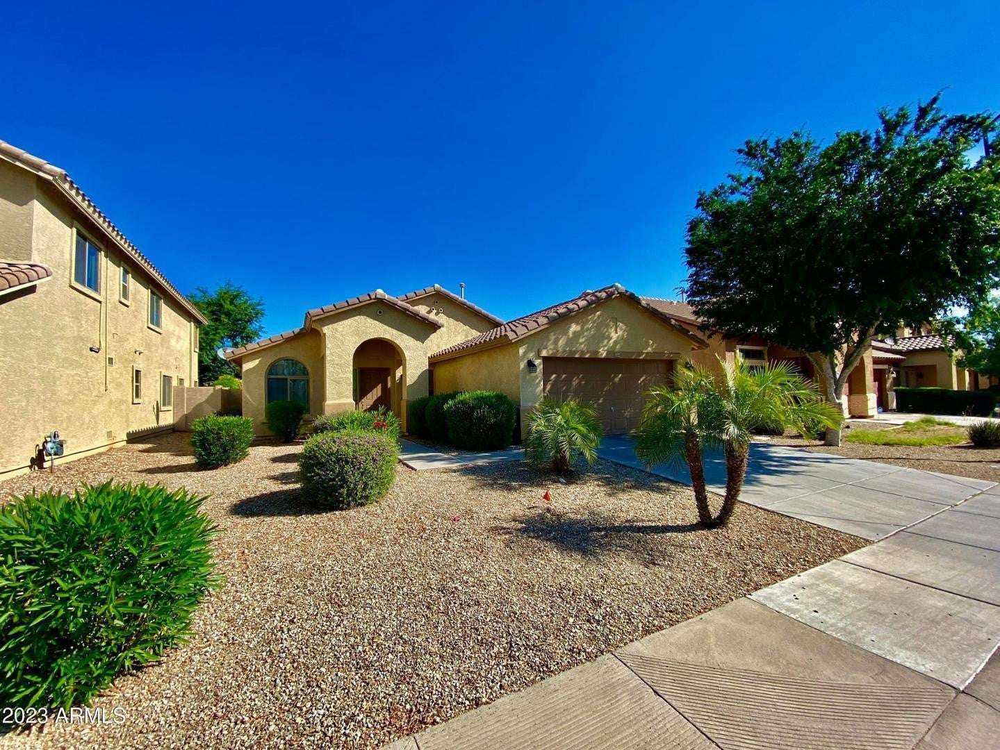 2 of 16. Professionally maintained desert landscaping with palm trees, decorative rock, and established greenery creates a welcoming first impression and easy outdoor maintenance.