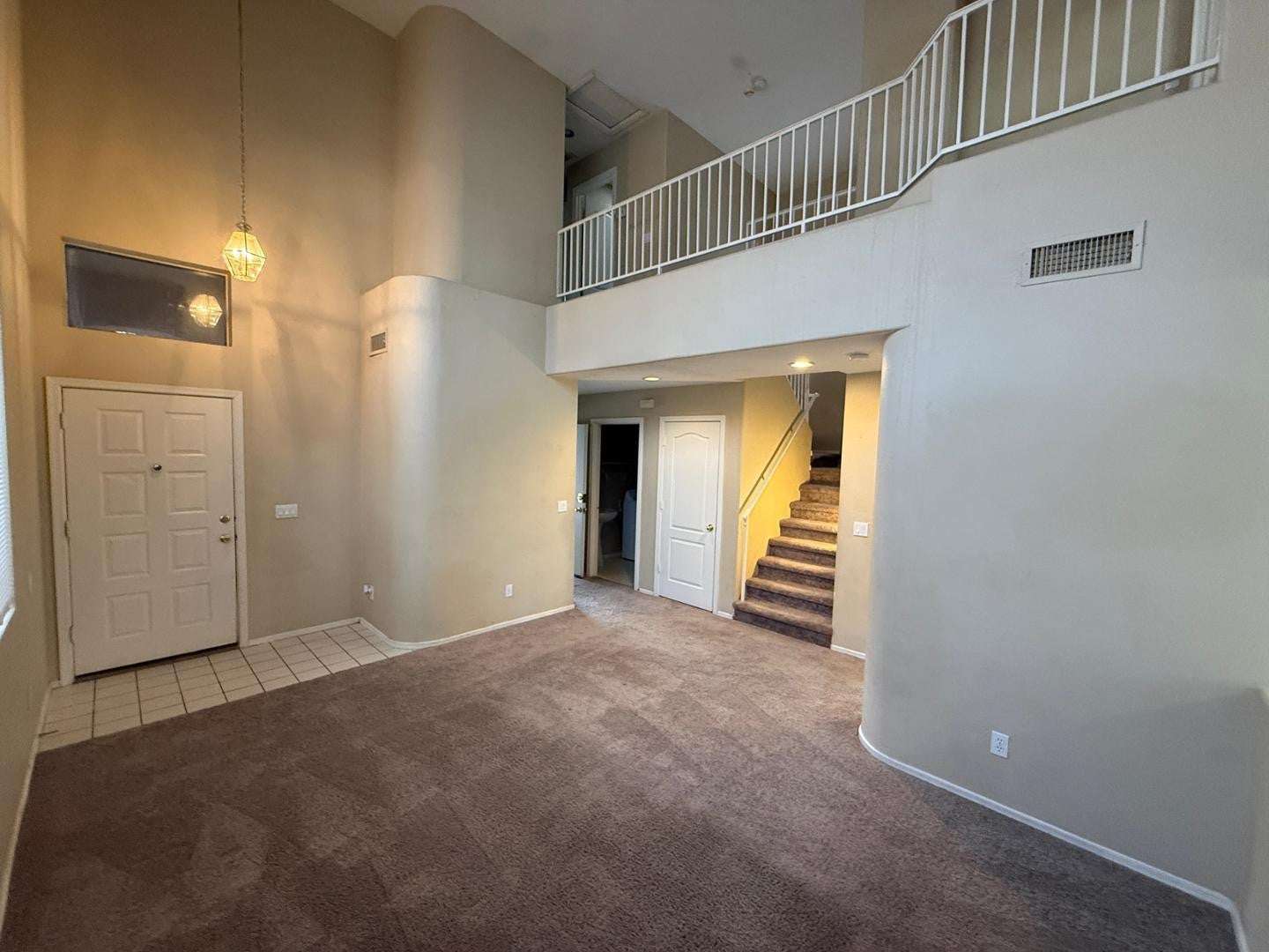 4 of 22. Dramatic vaulted ceilings and an open staircase create a striking focal point in this spacious living area. Natural light and neutral finishes provide a bright and welcoming environment.
