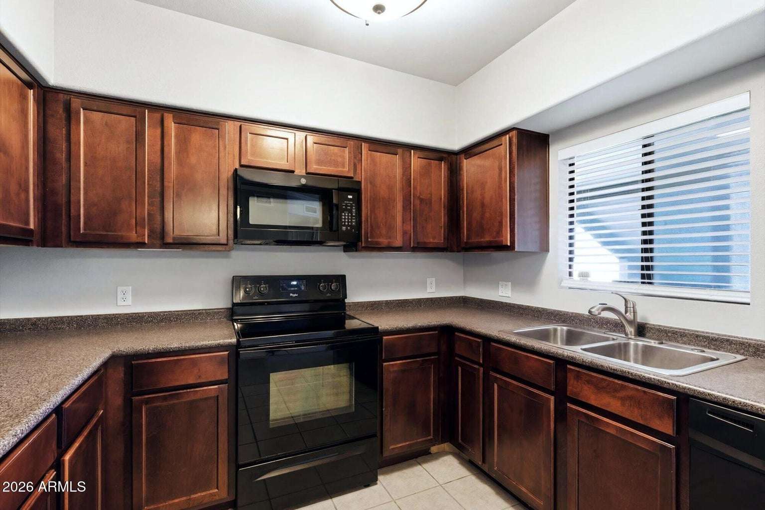 13 of 32. Rich wood cabinetry, generous countertops, updated appliances, and a convenient double-basin sink make this kitchen both practical and inviting. The efficient design supports everyday cooking with ease.