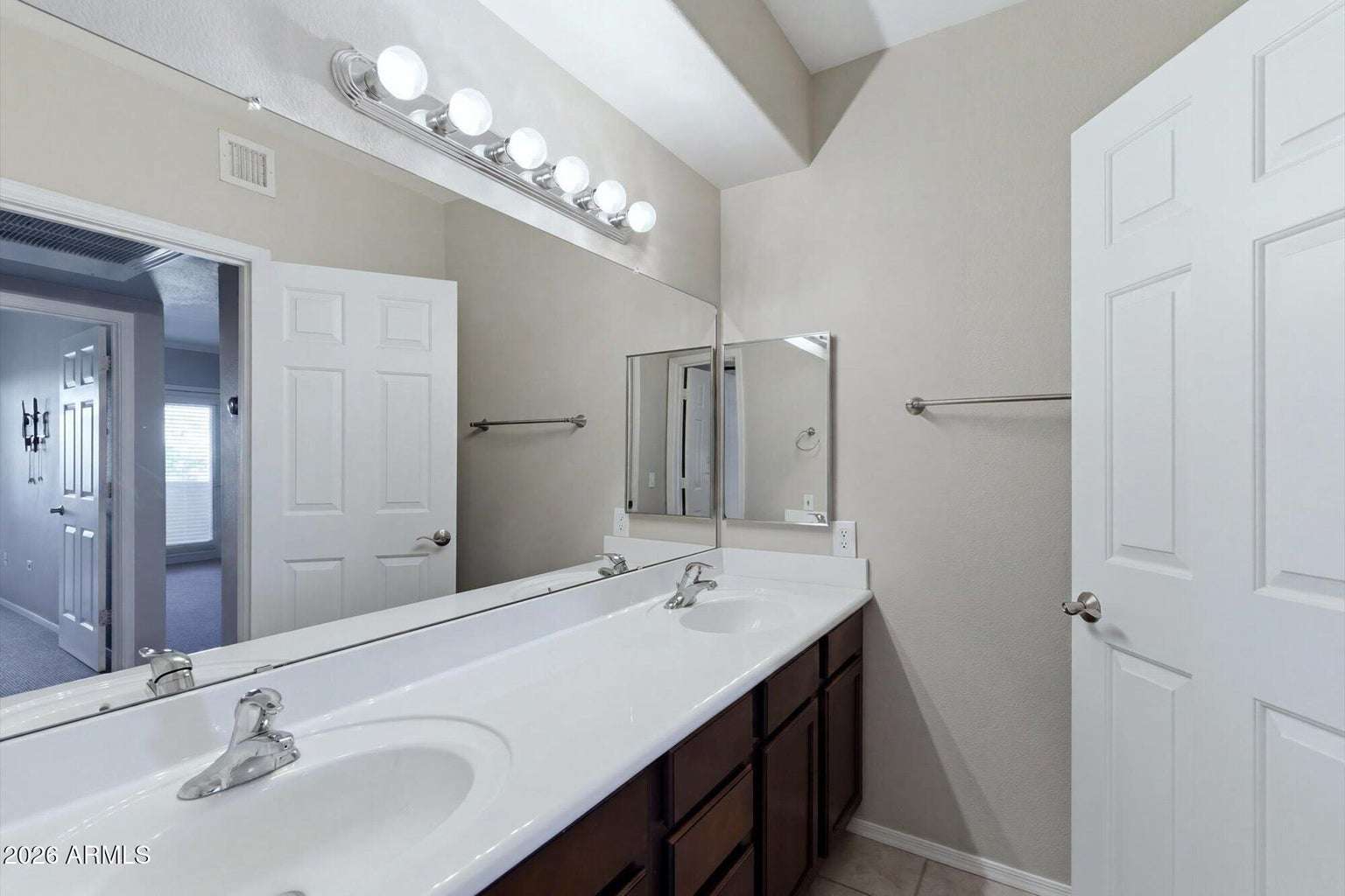 20 of 32. The bathroom showcases a dual-sink vanity with expansive countertop space, large mirror, and abundant cabinet storage, providing both convenience and functionality for everyday living.