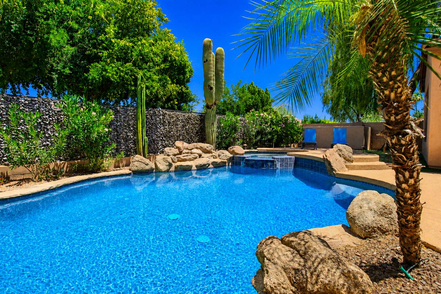 59 of 72. Beautiful landscaping surrounds the custom swimming pool and spa, creating a private backyard oasis with tropical plants, decorative boulders, and multiple spaces for outdoor enjoyment.
