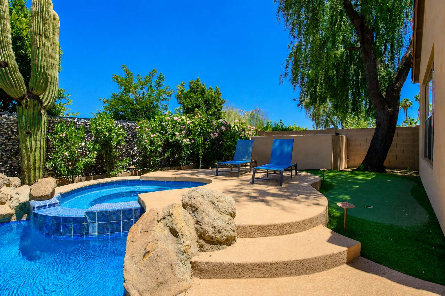 61 of 72. The raised spa and expansive lounging deck provide the perfect place to relax while surrounded by mature trees, artificial turf, and lush landscaping in this Scottsdale backyard.
