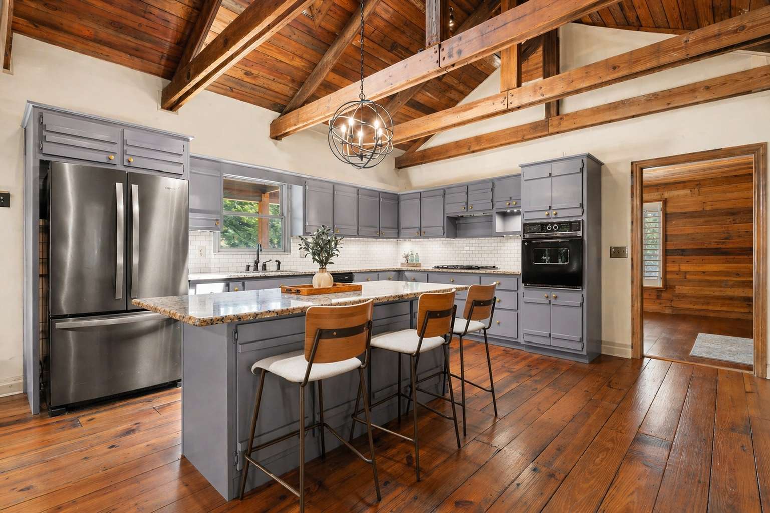 25 of 72. Modern kitchen featuring a spacious island, high ceilings, and rich wooden accents for a warm atmosphere.