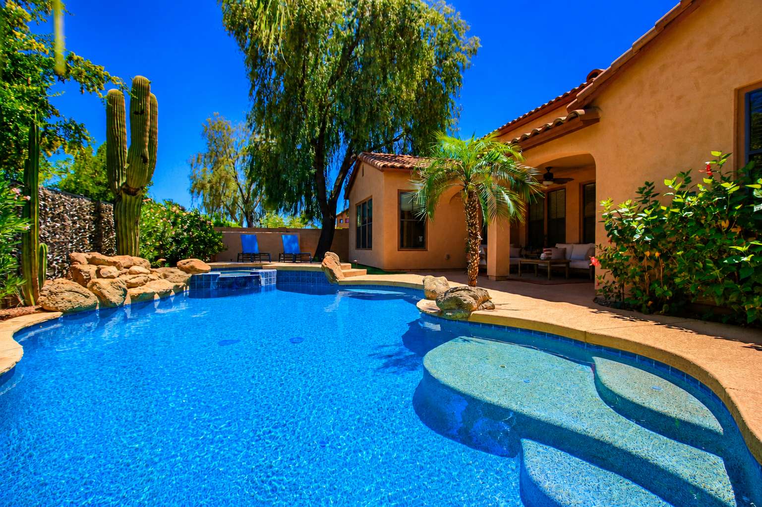 56 of 72. A resort-inspired backyard showcases a custom swimming pool with waterfall, elevated spa, tropical landscaping, mature trees, and covered patio for exceptional outdoor living.