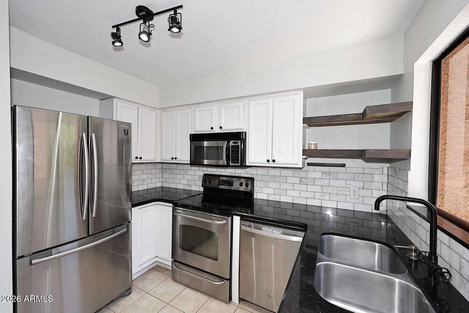 12 of 29. Bright kitchen with sleek countertops, stainless steel appliances, open shelving, and modern fixtures. Functional design and updated finishes create a welcoming heart of the home.