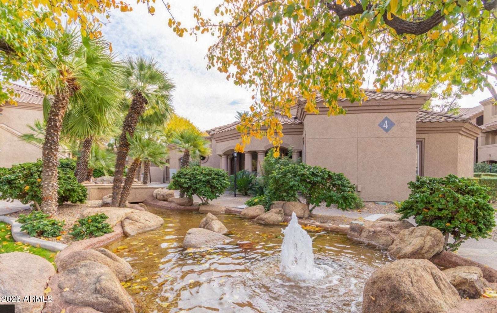 32 of 32. This beautifully landscaped courtyard features a decorative fountain, mature trees, natural stone accents, and lush greenery, creating a peaceful outdoor retreat within this highly desirable Scottsdale condominium community.