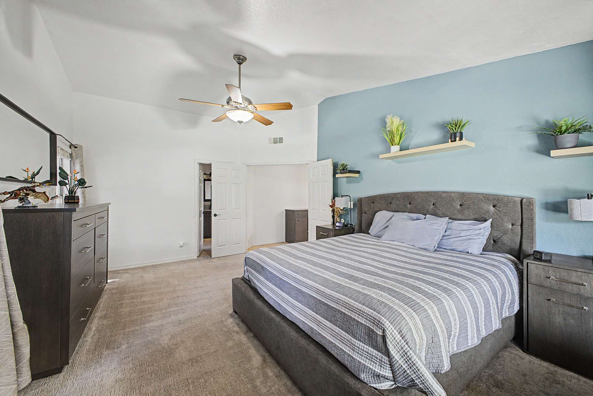 30 of 47. This generously sized bedroom offers a bright and airy atmosphere with vaulted ceilings, neutral colors, ceiling fan, and ample space for large furnishings while maintaining a relaxing feel.