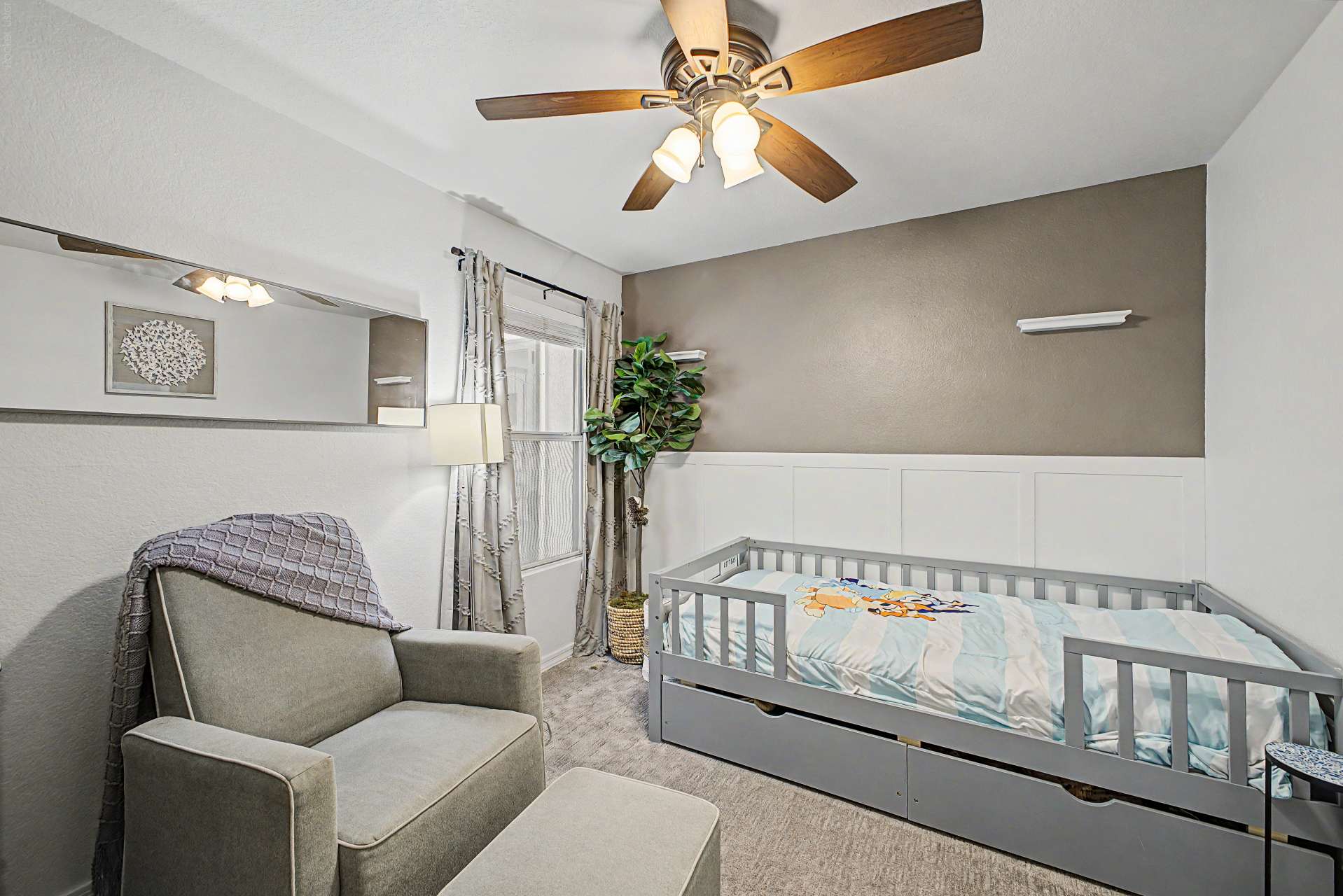 34 of 47. A welcoming secondary bedroom featuring plush carpeting, ceiling fan, stylish accent wall, and natural light. This flexible room works beautifully as a nursery, guest suite, or home office.