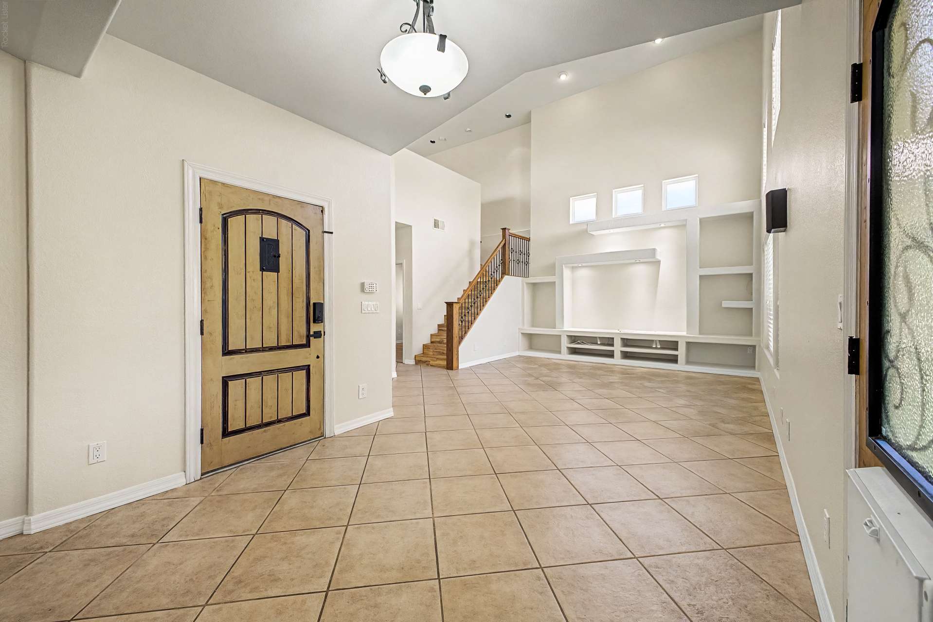 2 of 47. A welcoming front entry showcases soaring ceilings, elegant architecture, tile flooring, and a custom entertainment feature that creates a memorable first impression in this Glendale home.