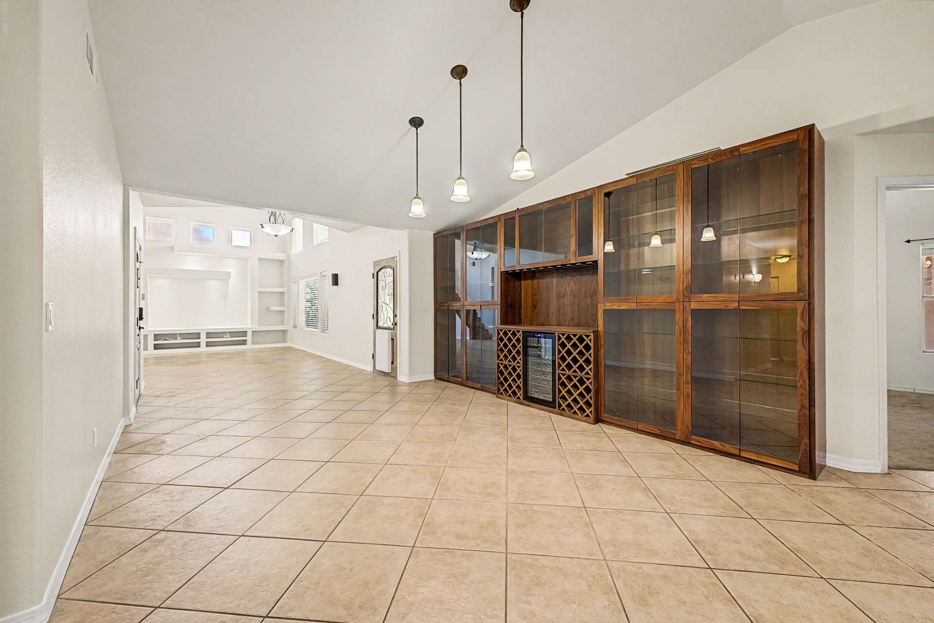 4 of 47. Floor-to-ceiling custom cabinetry with glass display shelves and integrated wine storage adds sophistication while providing exceptional storage and entertaining space within the home's open layout.