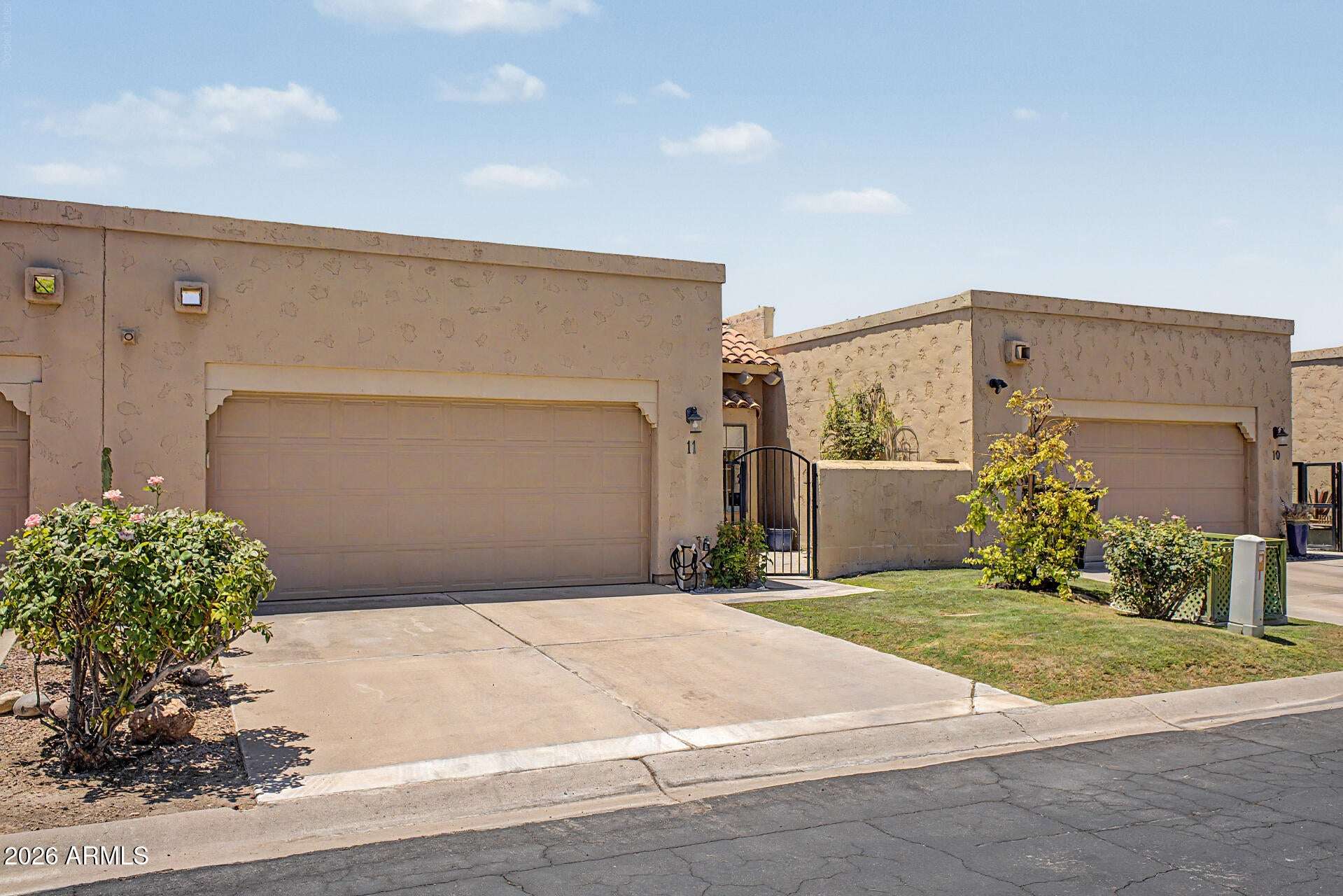 1 of 30. Front exterior view highlighting the oversized two-car garage, private gated entry, and attractive low-maintenance landscaping. This Scottsdale townhome offers convenience, privacy, and excellent curb appeal.