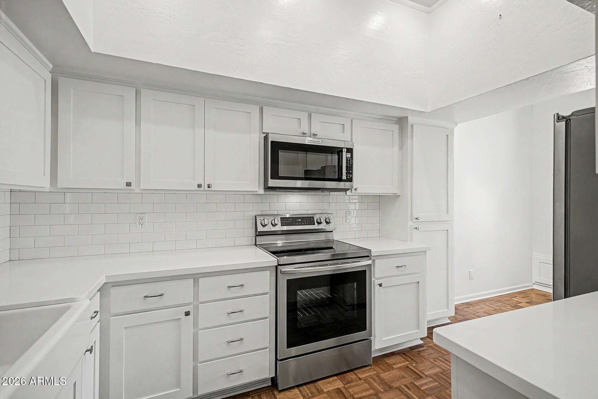 4 of 30. Updated kitchen showcasing crisp white shaker cabinets, stainless steel appliances, subway tile backsplash, and sleek countertops. The fresh design creates a bright and functional cooking environment.