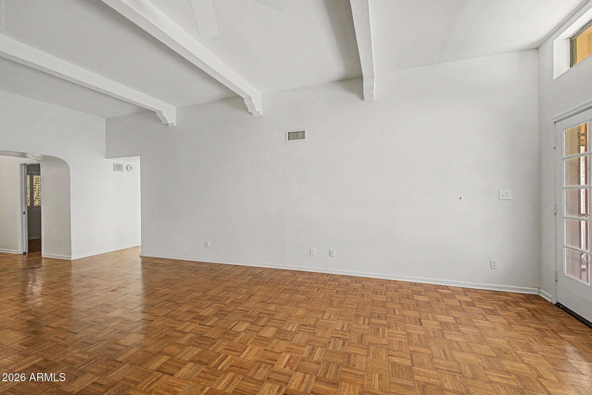 11 of 30. Open-concept living room showcasing soaring ceilings, exposed beams, and attractive parquet flooring. The spacious layout provides a welcoming environment for everyday living and entertaining.