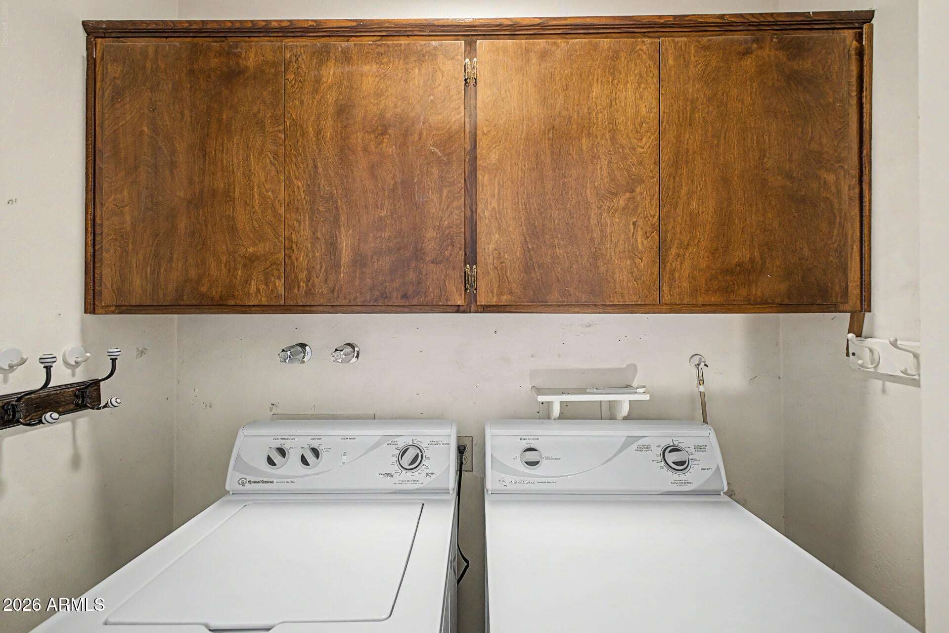 22 of 30. Well-equipped laundry area with overhead storage cabinets, washer and dryer setup, and practical organization space. Designed to support convenient household routines.