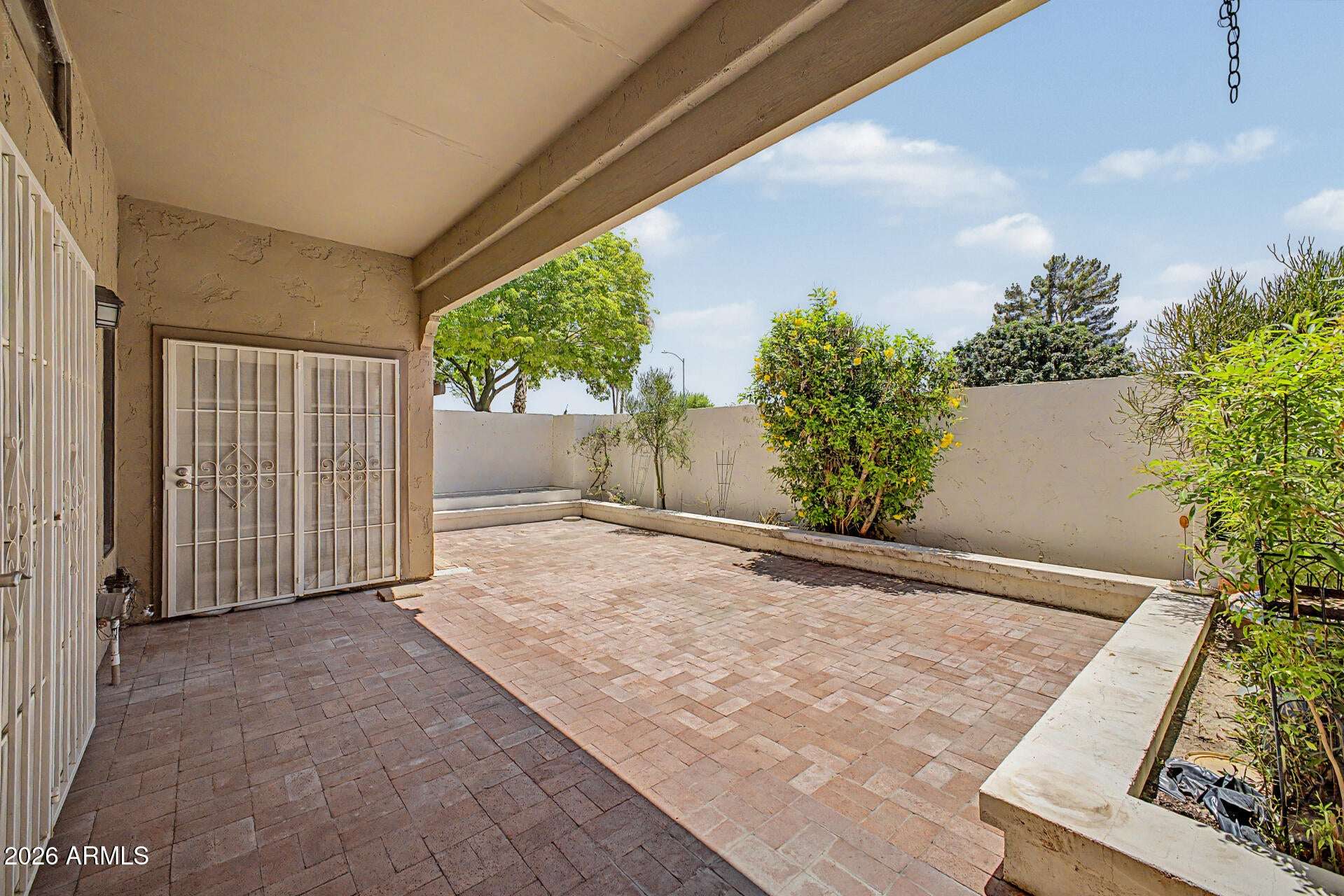 24 of 30. Shaded patio featuring attractive paver finishes and privacy-enhancing walls. This comfortable outdoor space is ideal for entertaining guests or enjoying quiet mornings outdoors.