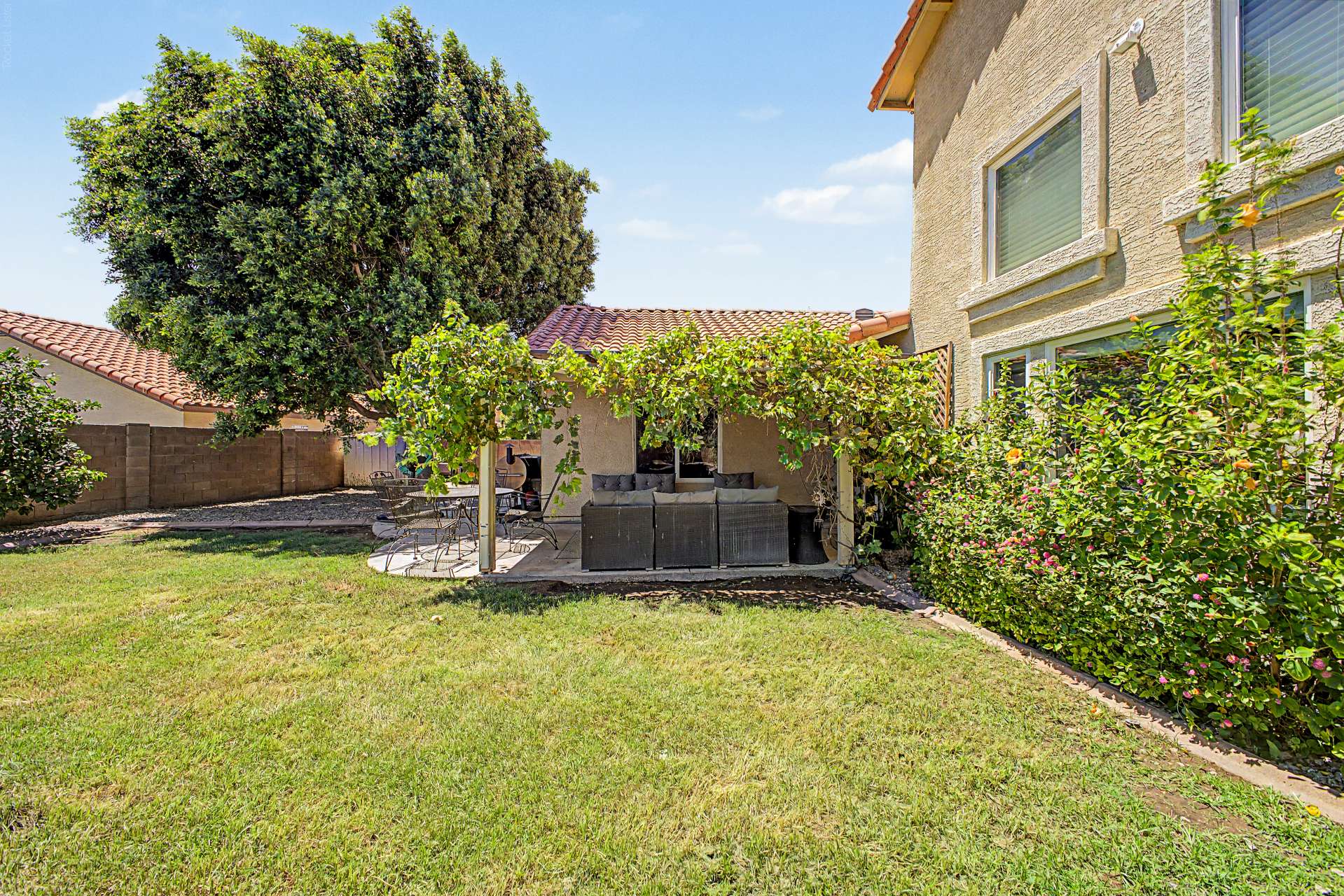 46 of 47. This private backyard showcases mature landscaping, lush grass, established shade trees, and a covered patio, offering a comfortable outdoor setting with plenty of room to enjoy Arizona living in Glendale.