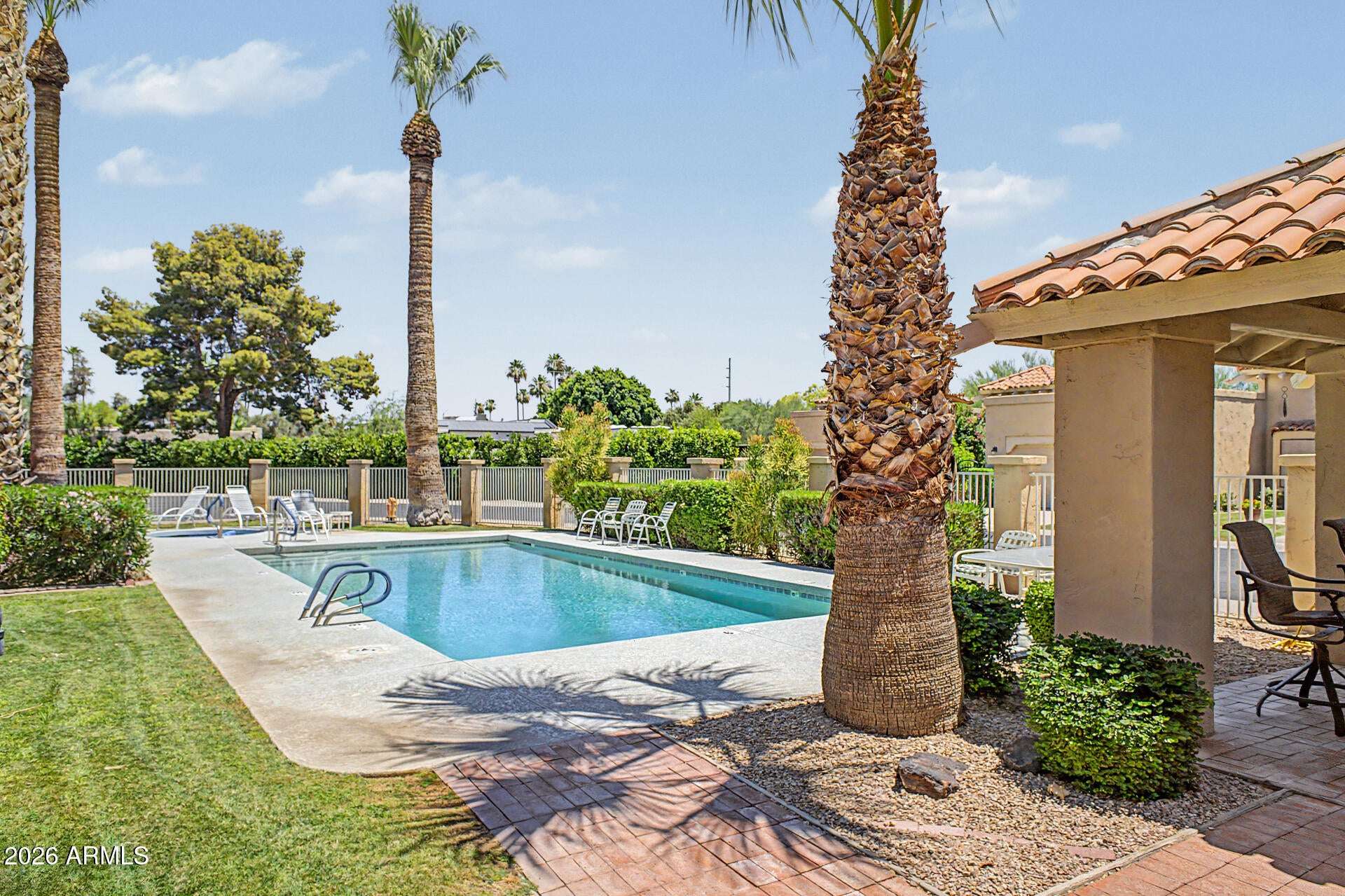 29 of 30. Resort-inspired community pool area featuring a shaded ramada, mature palm trees, and relaxing outdoor seating. An excellent amenity for recreation and social gatherings.
